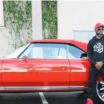 Queen’s King supporter in a hoodie beside a red classic car